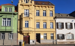Historická budova s žlutou fasádou v ulici v Brně za slunečného dne