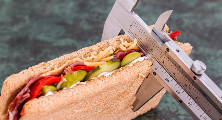 Sendvič měřený posuvným měřítkem jako symbol dietního režimu nebo kontroly porcí