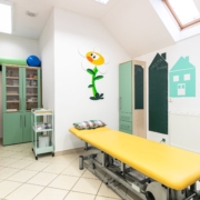 Dětská fyzioterapeutická ordinace s barevnou výmalbou, lehátkem a úložným nábytkem.