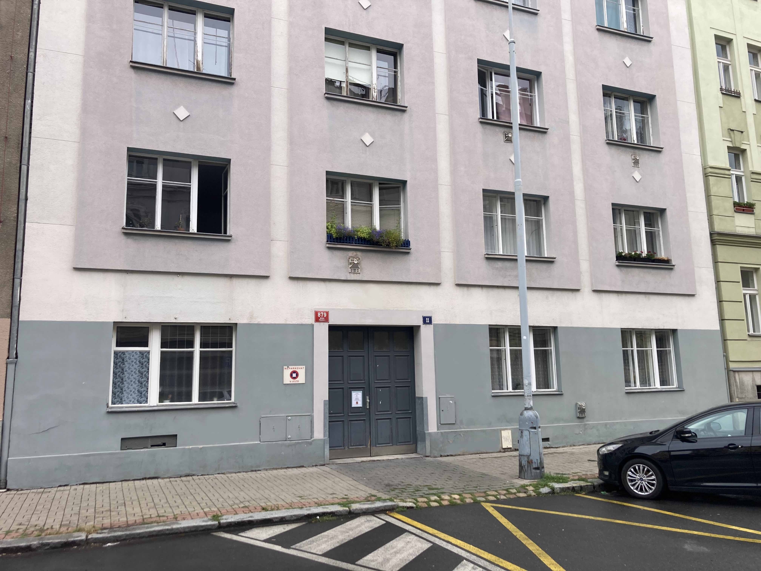 Vchod do pobočky Sarema v Praze na adrese Jeremenkova 11, s parkovacími místy před budovou.