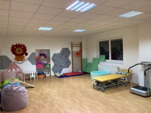 Rehabilitační místnost kliniky Sarema s terapeutickou žíněnkou, balančními pomůckami a žlutým lehátkem.