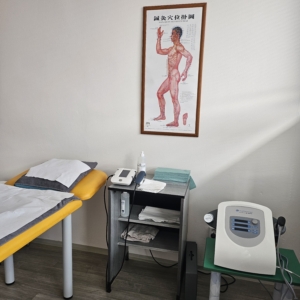 Fyzioterapeutická místnost s lehátkem, přístroji a anatomickým plakátem